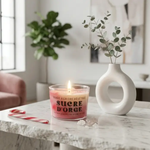 Bougie artisanale à la cire végétale parfum Sucre d'Orge Allume Tes Sens posée sur une table en marbre dans un salon moderne et élégant