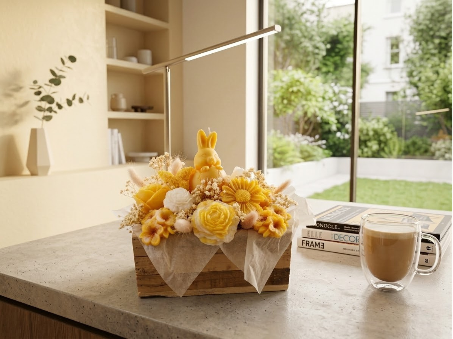 Composition de Pùques jaune avec bougie lapin et fleurs en cire sur un comptoir moderne à cÎté d'une tasse de café.